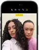 iPhone 18 Pro, black, front exterior, displaying two models posing for the camera, demonstrating the Center Stage front camera