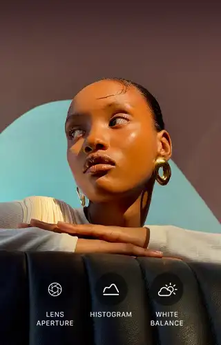 Close-up portrait of a well-lit model with a colourful background, demonstrating the pro camera system's Pro controls UI: Aperture, Histogram, White Balance