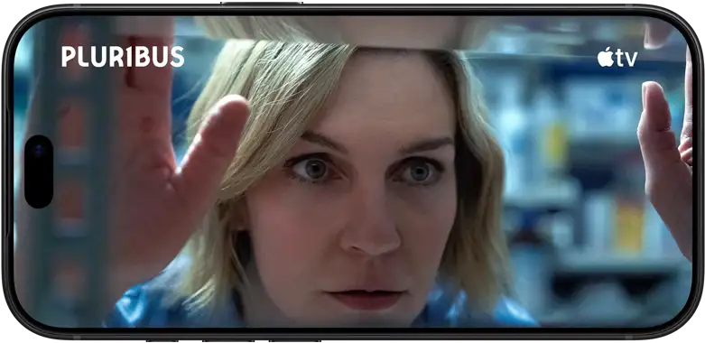 iPhone 18 Pro, landscape mode, displaying a close-up of a woman looking through a window. Series title: Pluribus