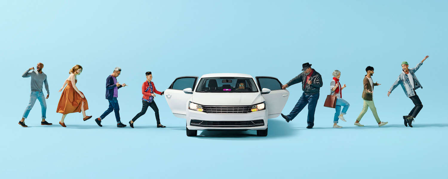 A line of eight people getting in and out of a white Lyft with a pink Amp in the windshield.