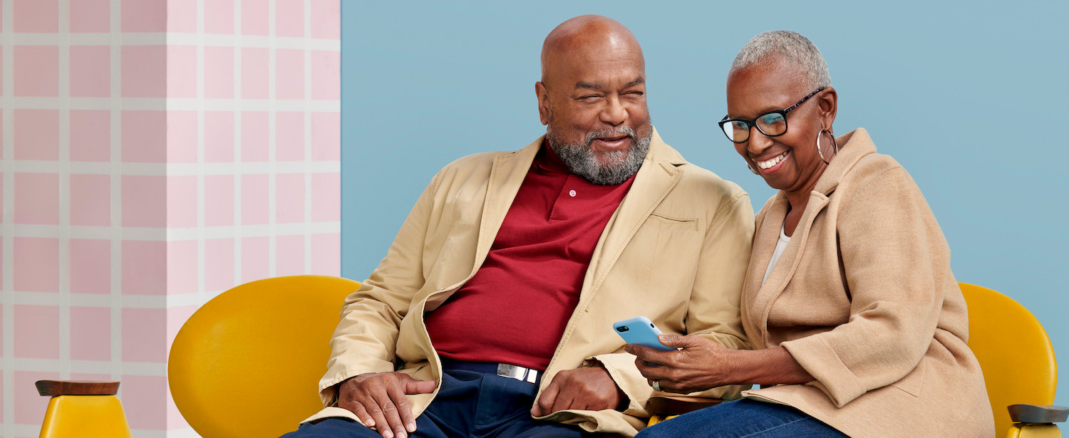 A couple smiling and looking at their cell phone