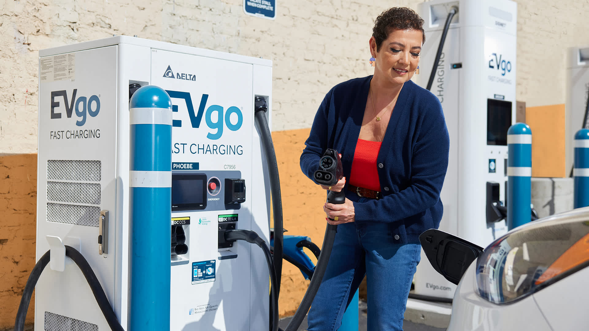 Woman charging EV car at EVgo charging station.