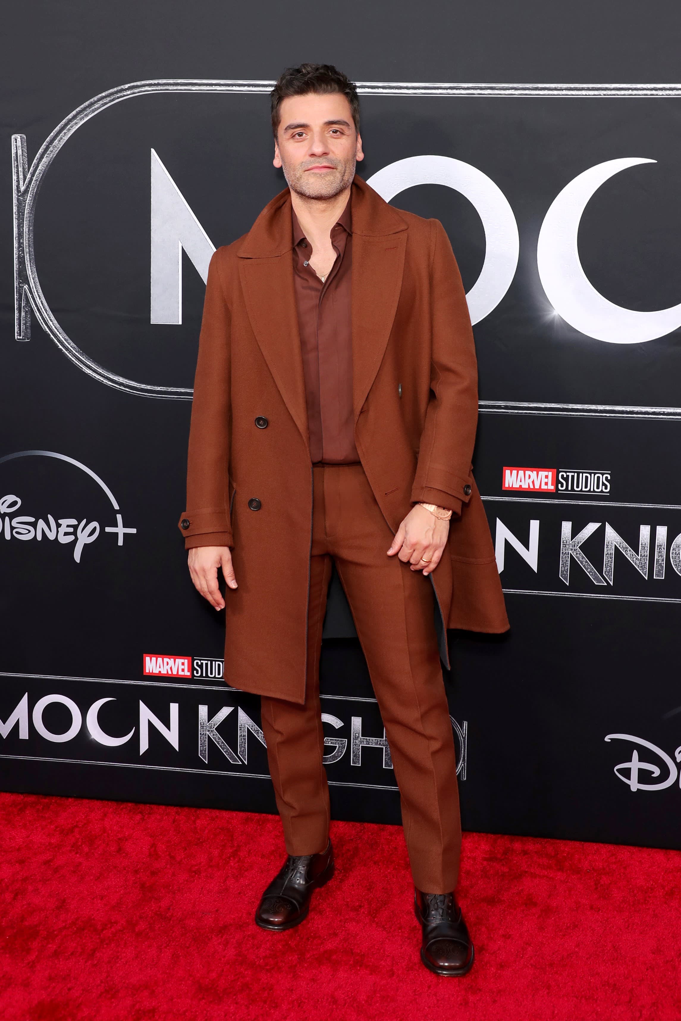 Oscar Isaac wearing a Brioni brown suit with coat