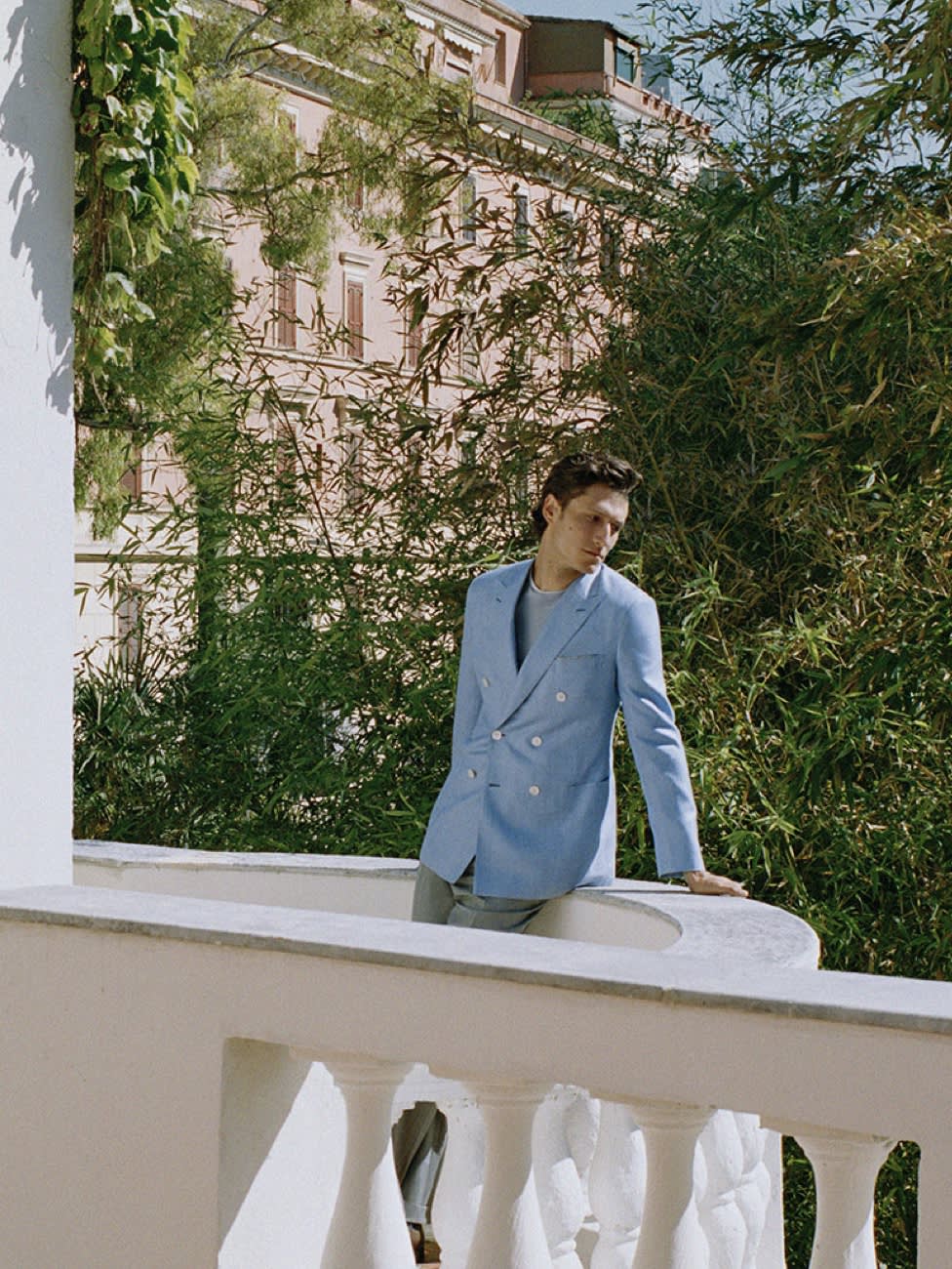 Male model wearing a light blue double-breasted jacket and grey trousers