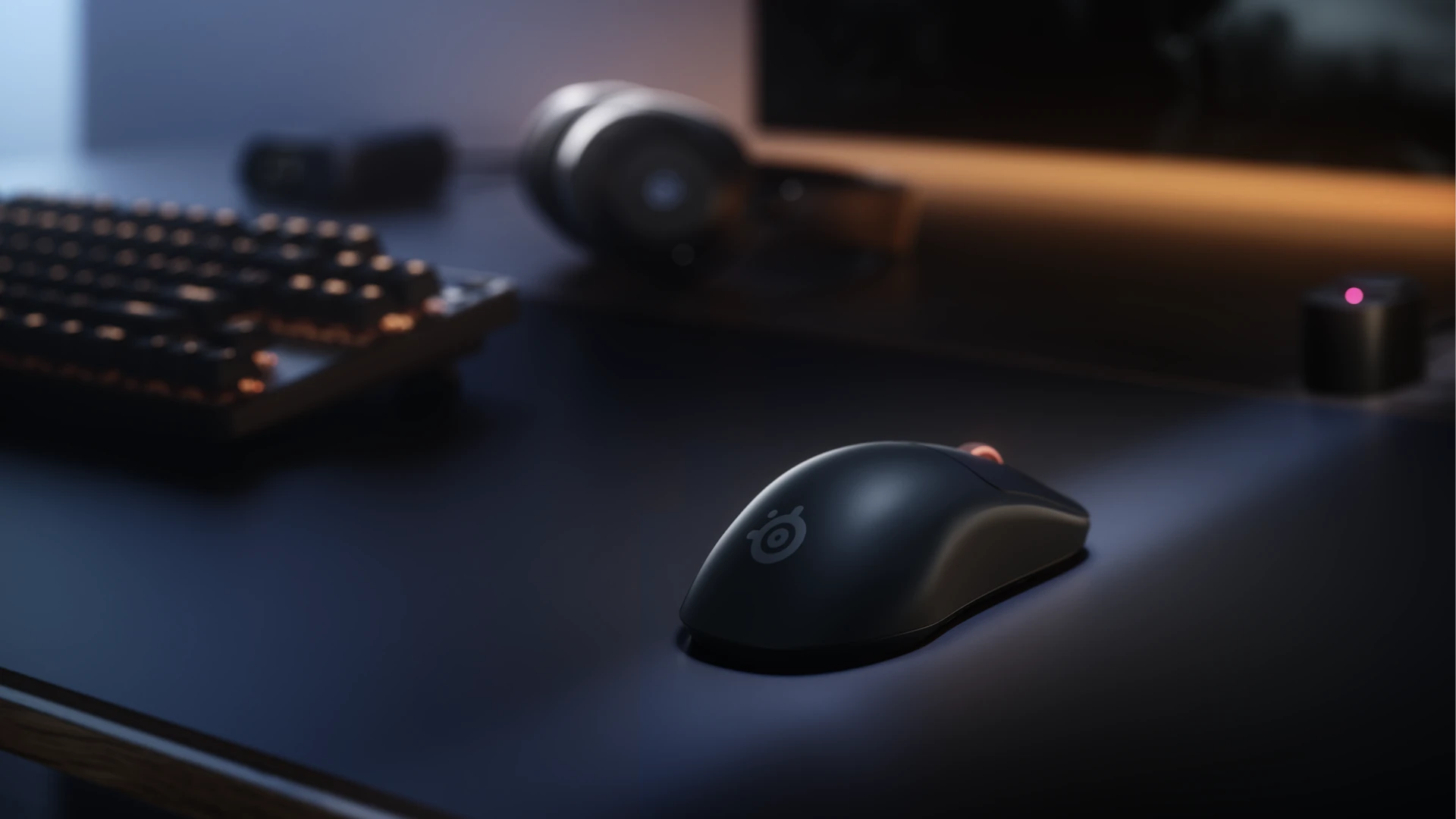 Angled rear view of the matte black Sensei Pro gaming mouse resting on a desk alongside a mechanical keyboard and wireless headset.