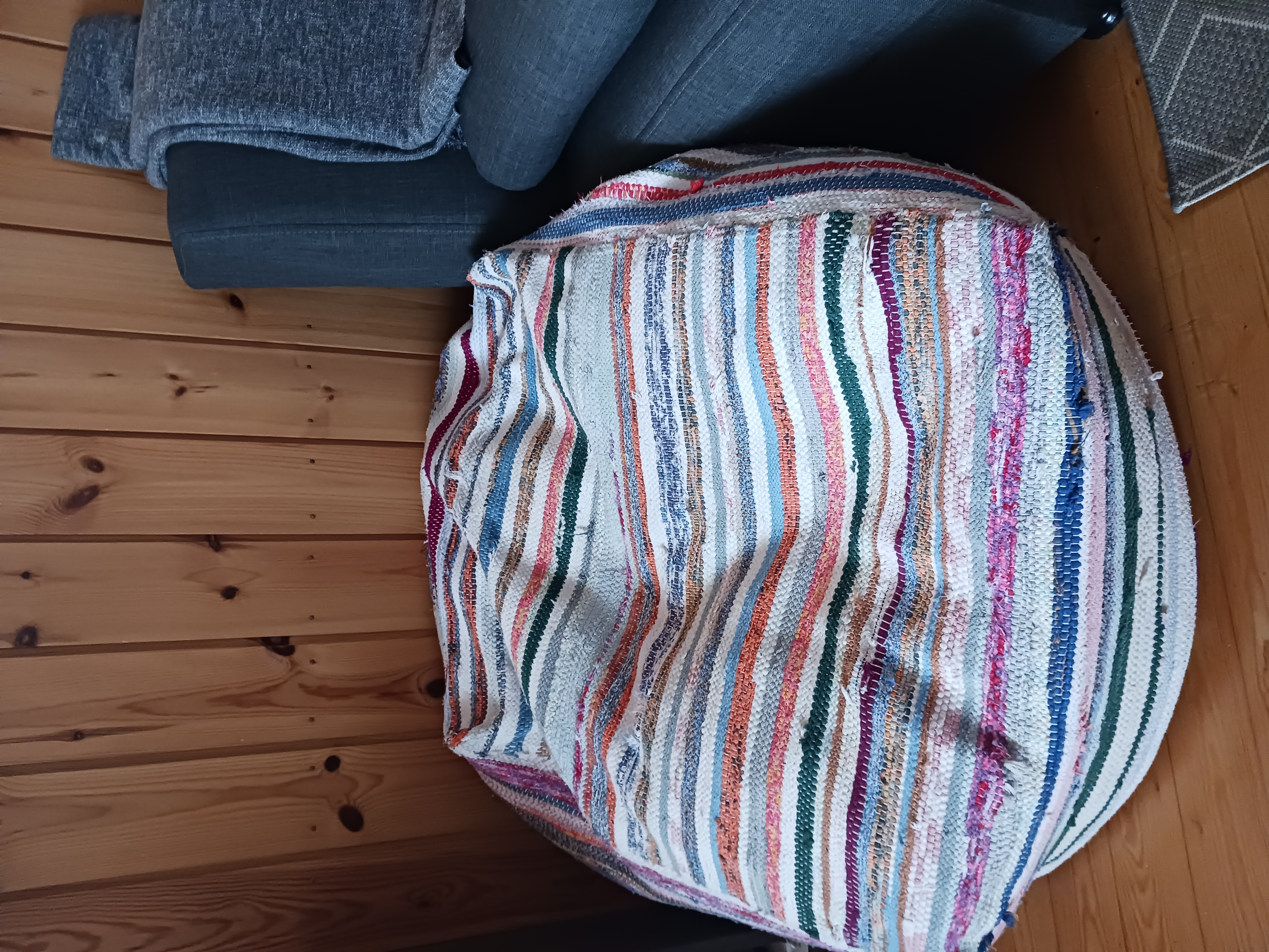 raidallisella räsymatolla päällystetty säkkituoli edestä, vieressä sohva