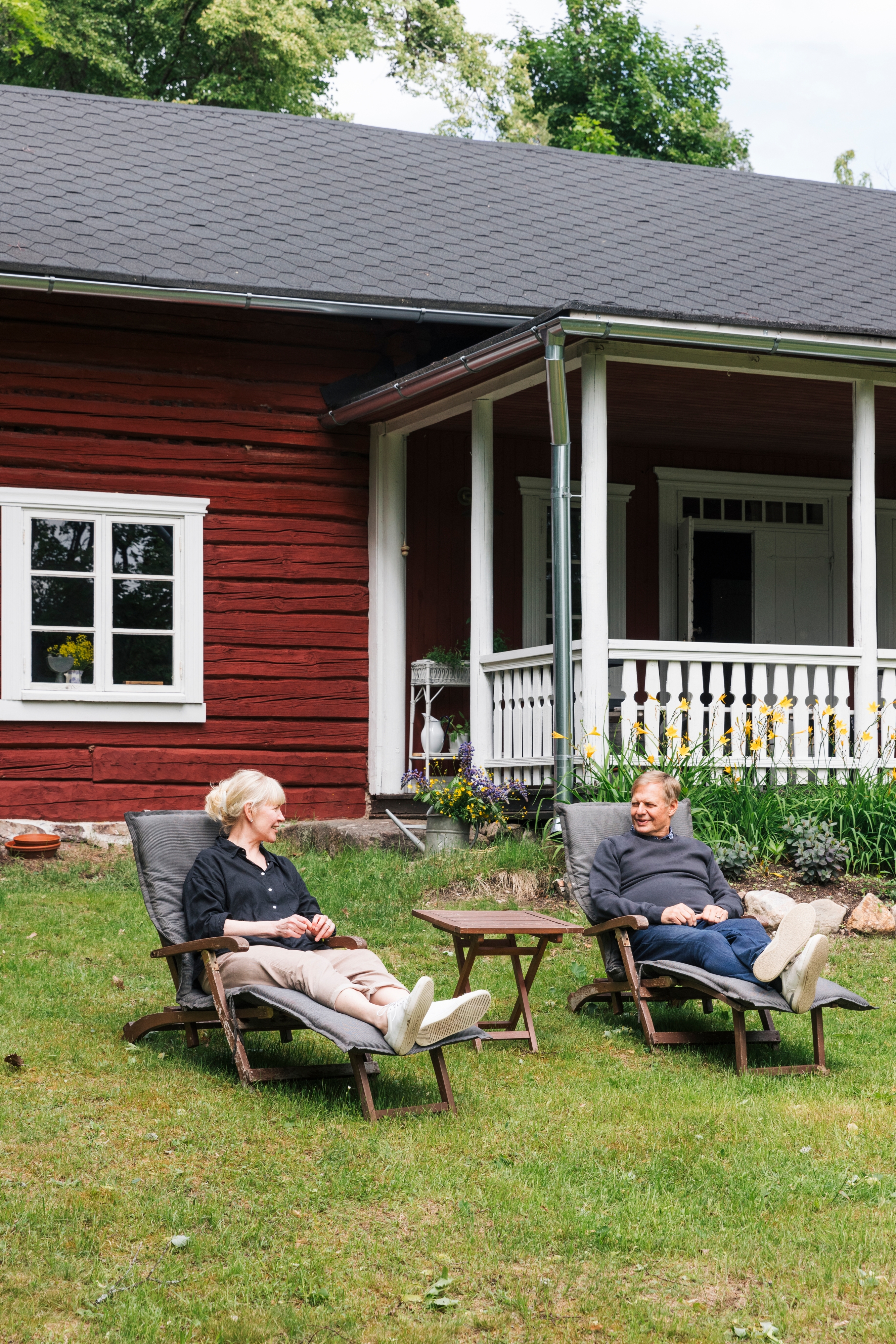 Anne Pakomäki ja Heikki Hyttinen aurinkotuoleissa Korsnäsin talon edustalla