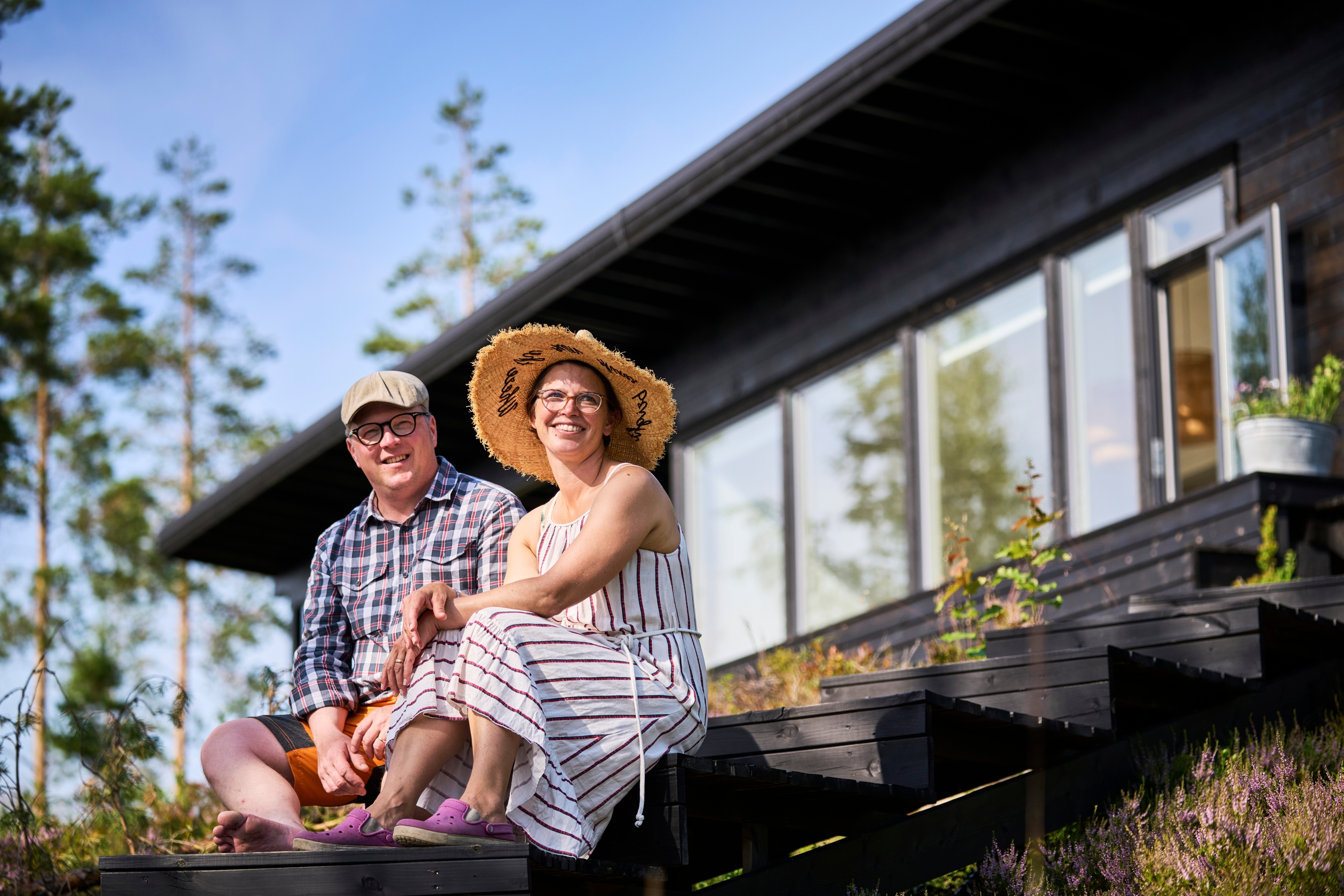 mies ja nainen istuvat portailla jotka vievät mustalle kesämökille