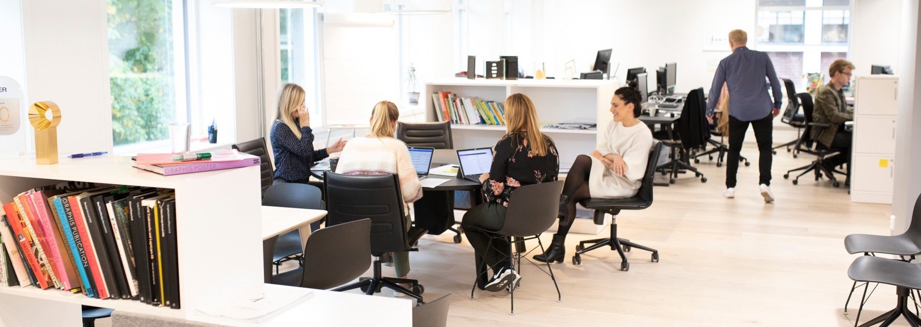 Many people working at the Oslo office - some sitting in a group, others by their desks.