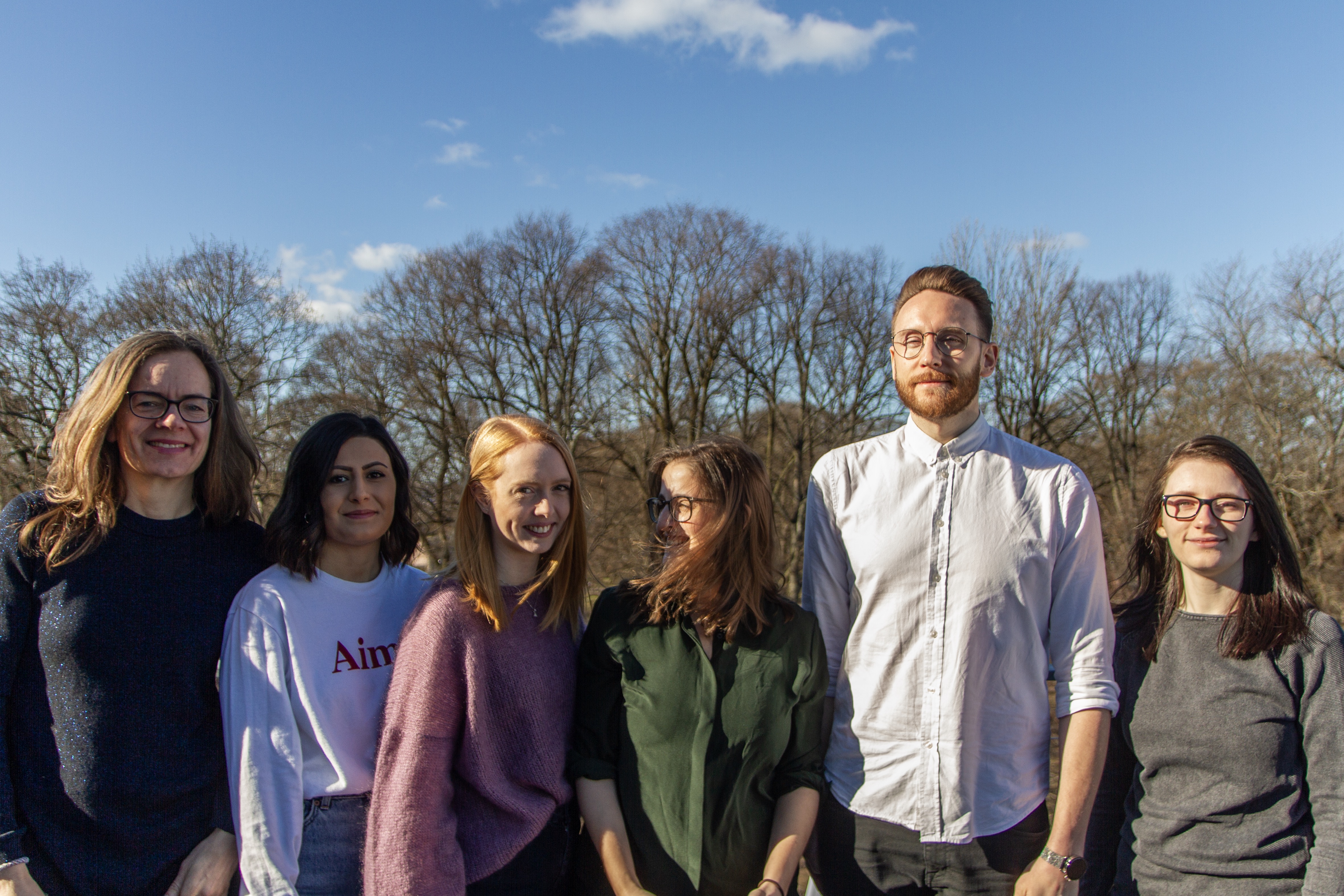 Group of people lined up beside eachother, smiling at the camera