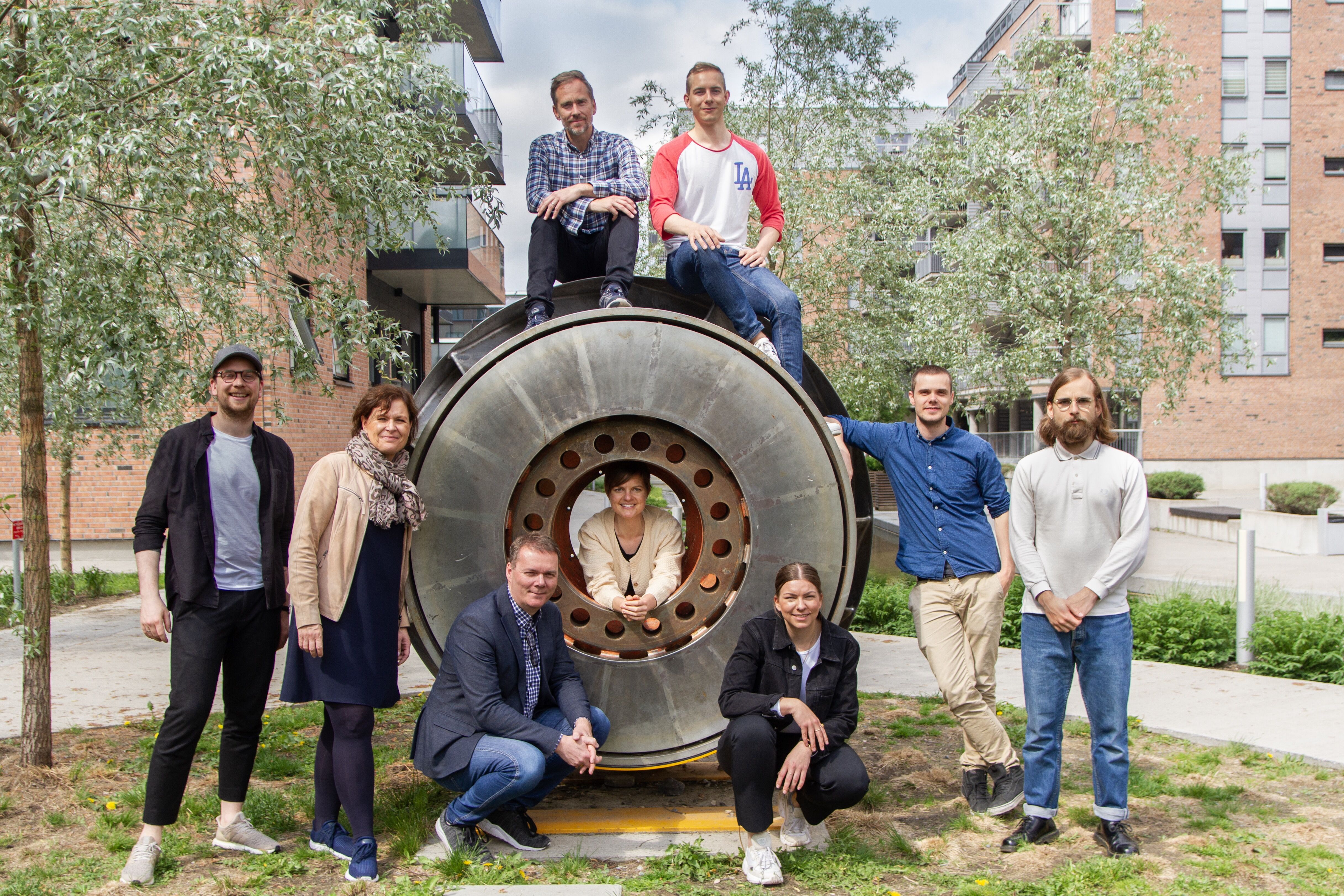 A group of people gathered around and on top of a round metal construction, smiling at the camera.