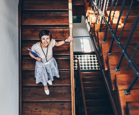 Seen from above: A woman looking up while walking down a flight of stairs, smiling.