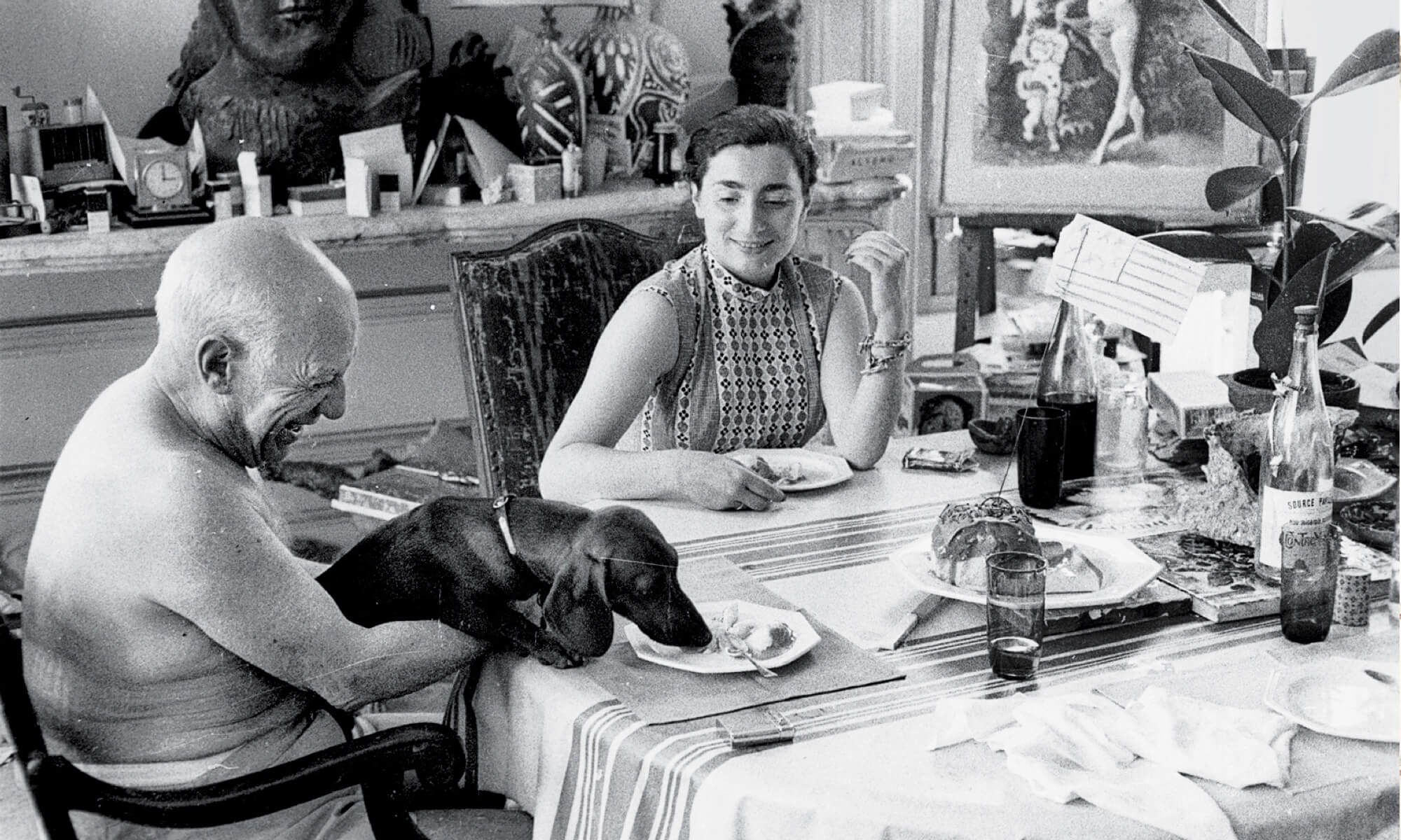 Picasso, wife Jacqueline and his dog at dining room table with buffet table