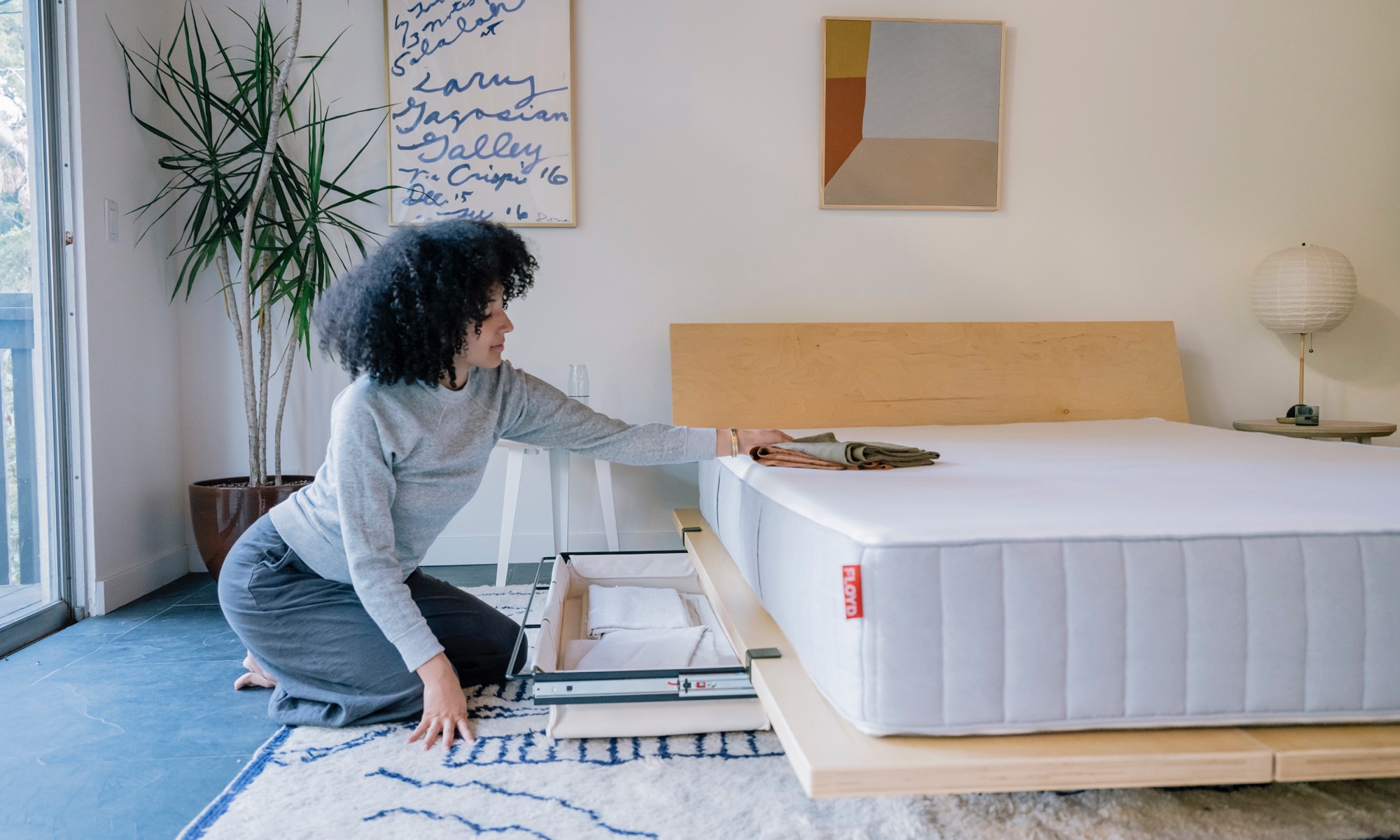 woman in bedroom unpacking storage from Floyd platform bed drawer