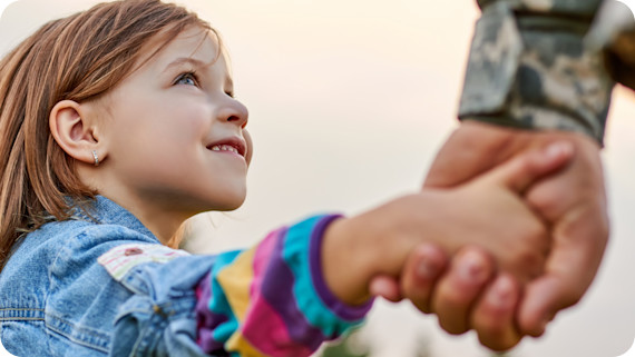 Young child holding hands with army officer