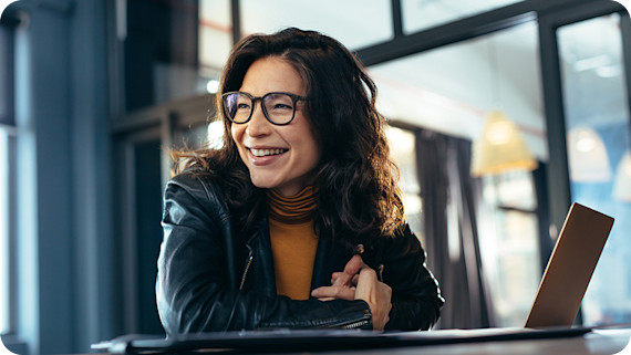 About Us Smiling businesswoman at office with laptop.