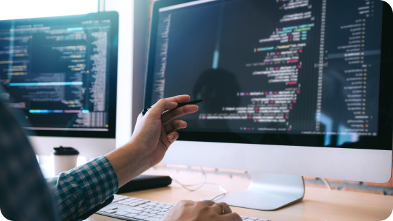 Software developer holds the pen pointing to the computer screen and is analyzing the code.