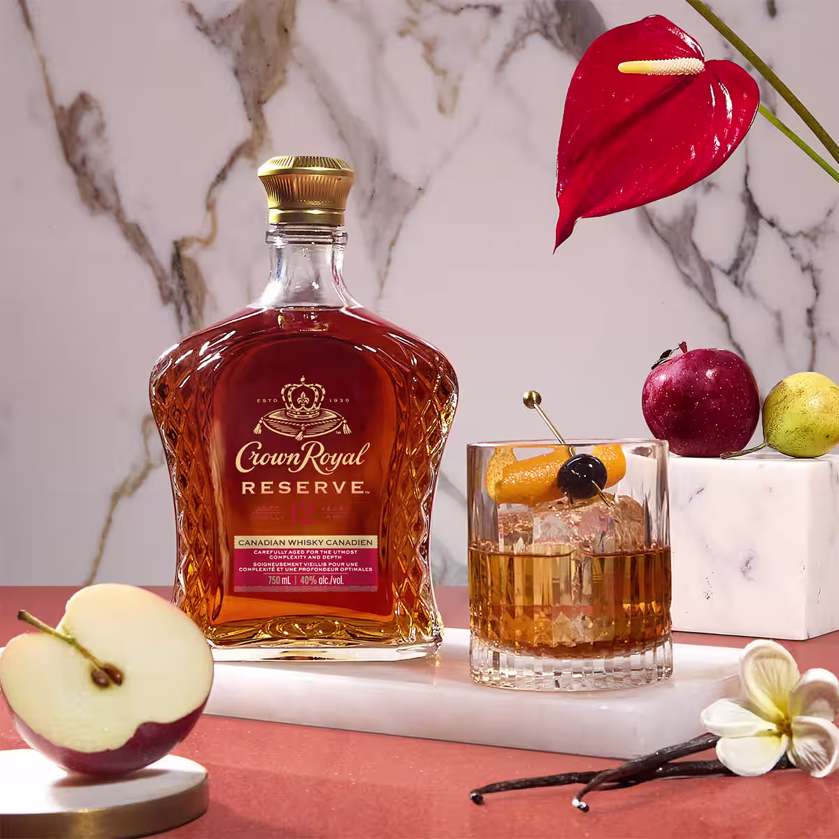A bottle of Crown Royal Reserve on a table next to a Old Fashioned cocktail