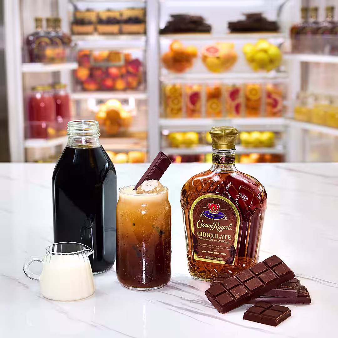A bottle of Crown Royal Chocolate next to a chocolate whisky and iced coffee cocktail