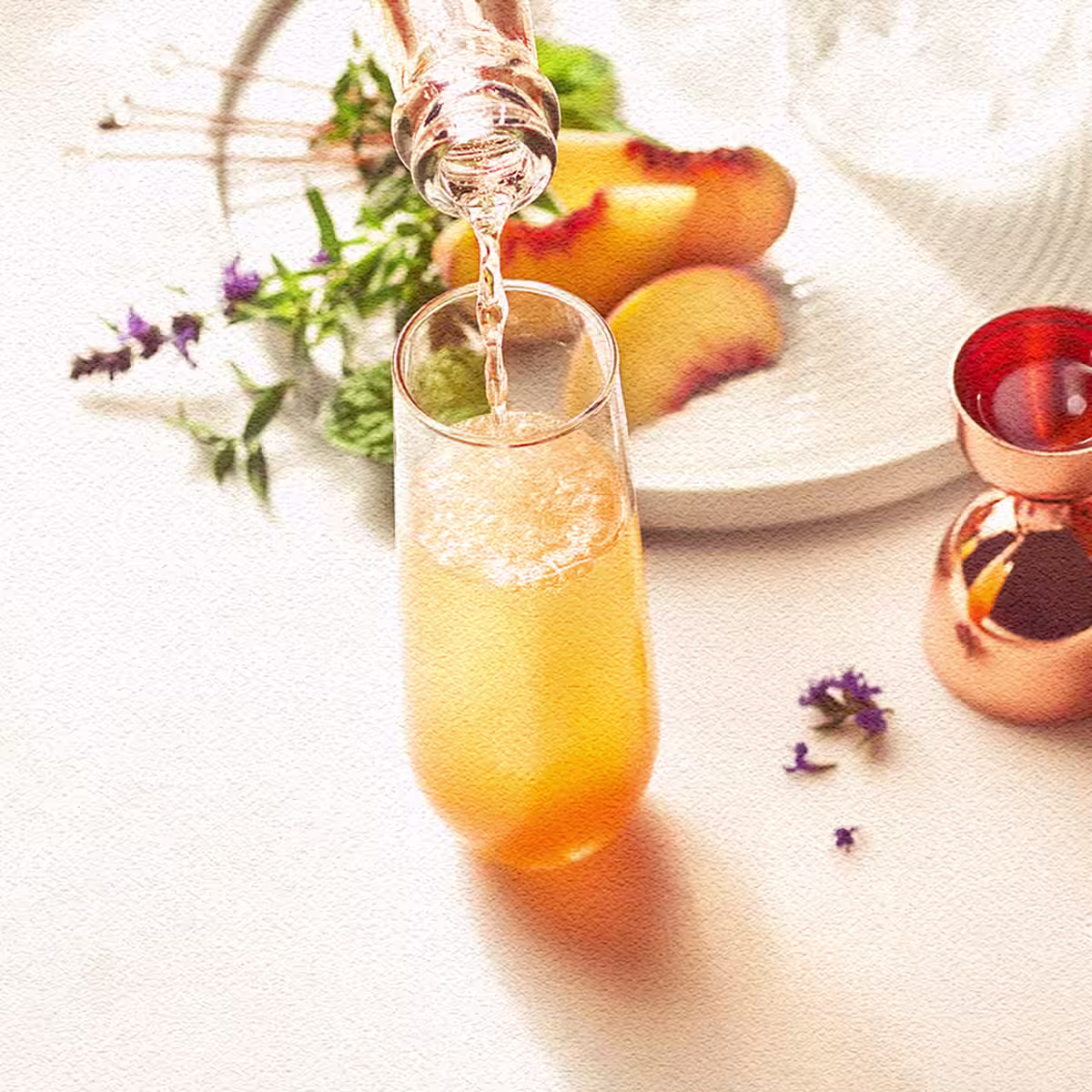 A Royal Peach Fizz cocktail being poured into a flute glass
