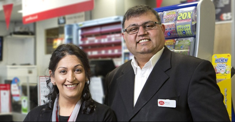 Two people standing in front of a Post Office counter