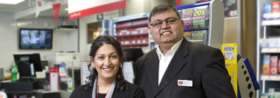 Two people standing in front of a Post Office counter