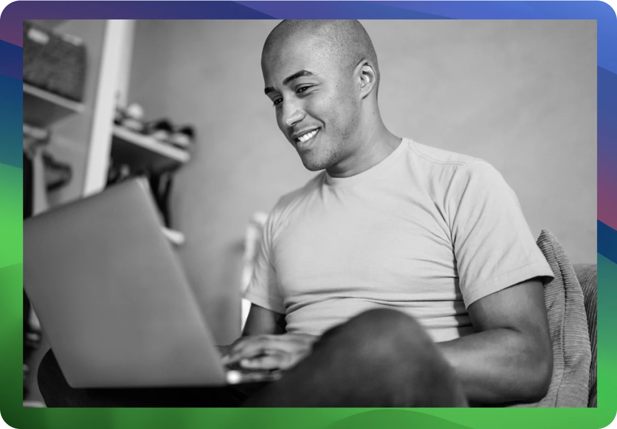 man smiling sitting and using macbook