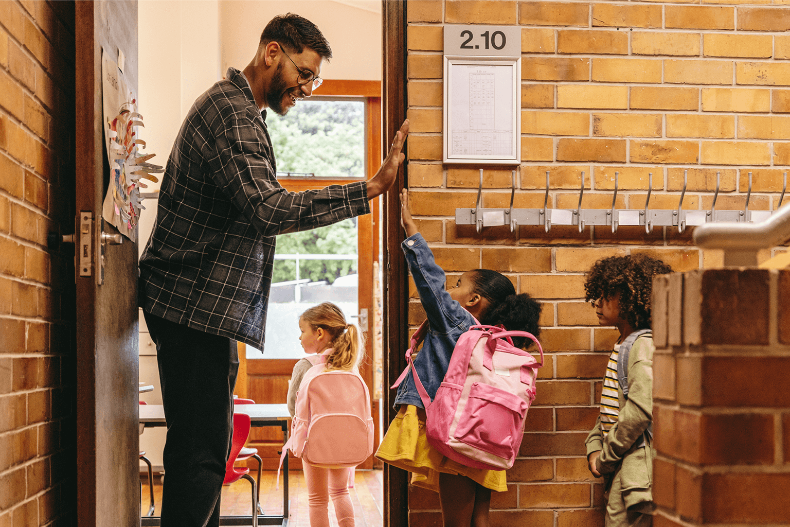 Kids giving high fives to the teacher as they walk into the classroom.  Kids giving high fives to the teacher as they walk into the classroom.
