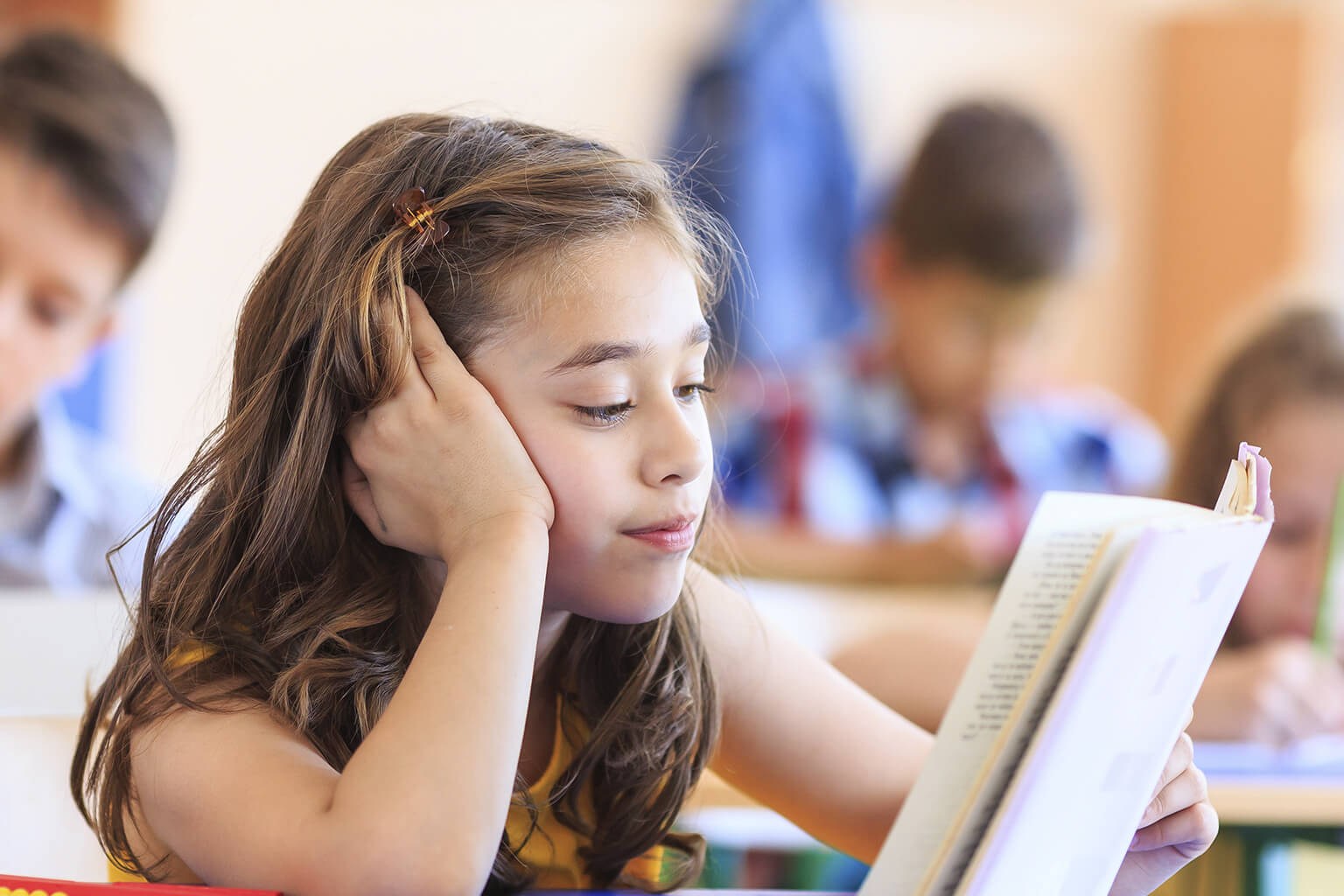 A child reading a book at their desk. A child reading a book at their desk.