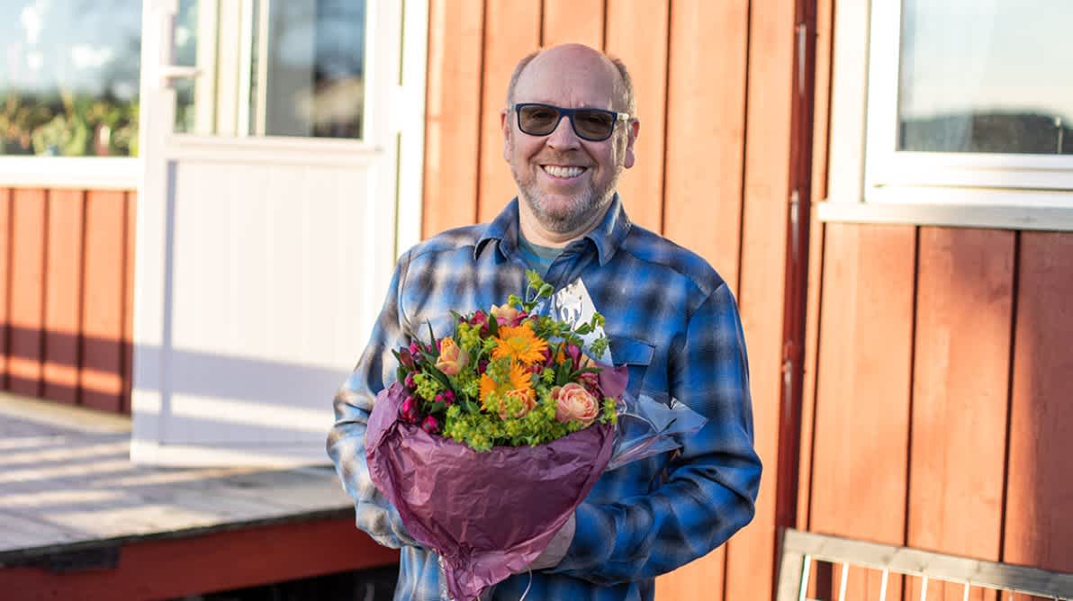 Reimund Geving holder en bunke blomster og smiler til kamera