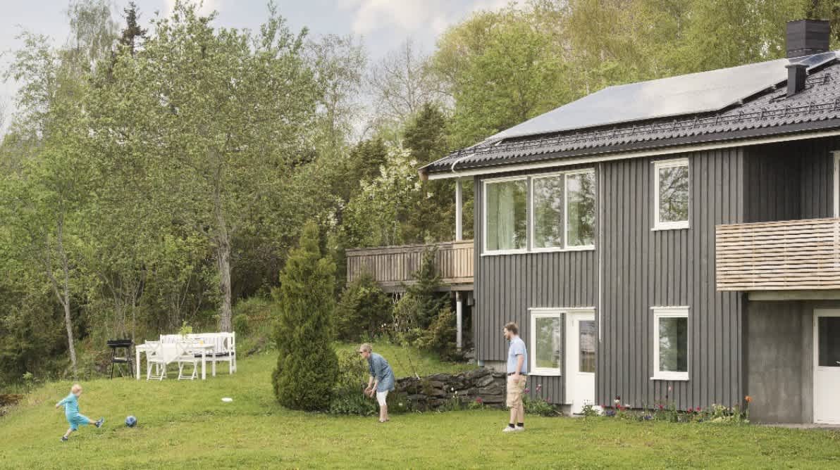 Hus med solceller med familie ute i hagen
