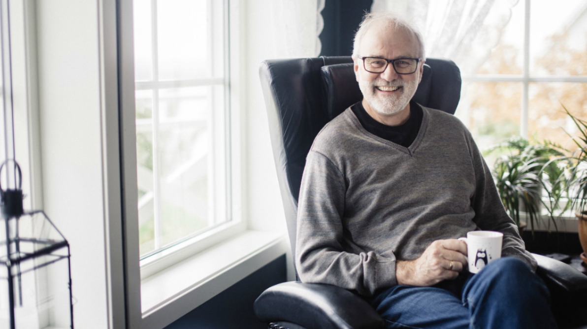 Bilde av John Ivar Aalberg som sitter i en stol med en kopp kaffe