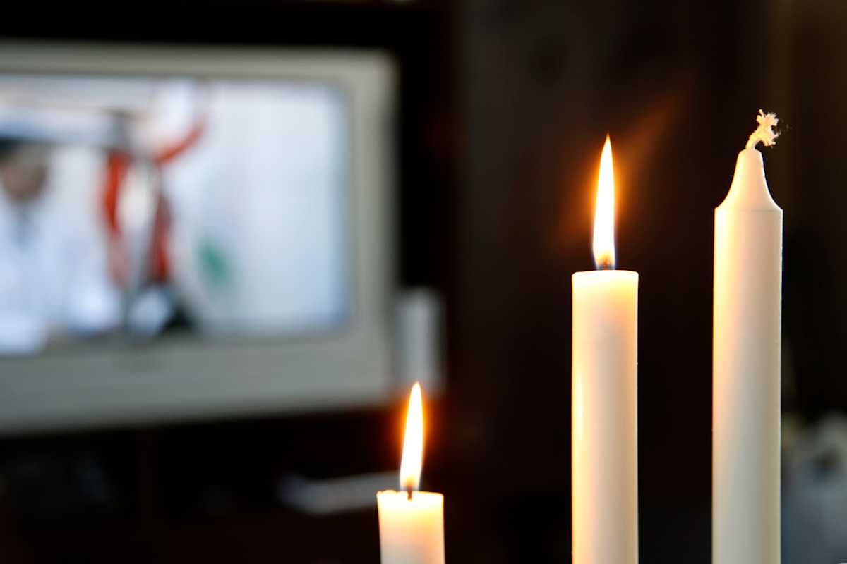 Adventsstake med to brennende lys foran en tv-skjerm