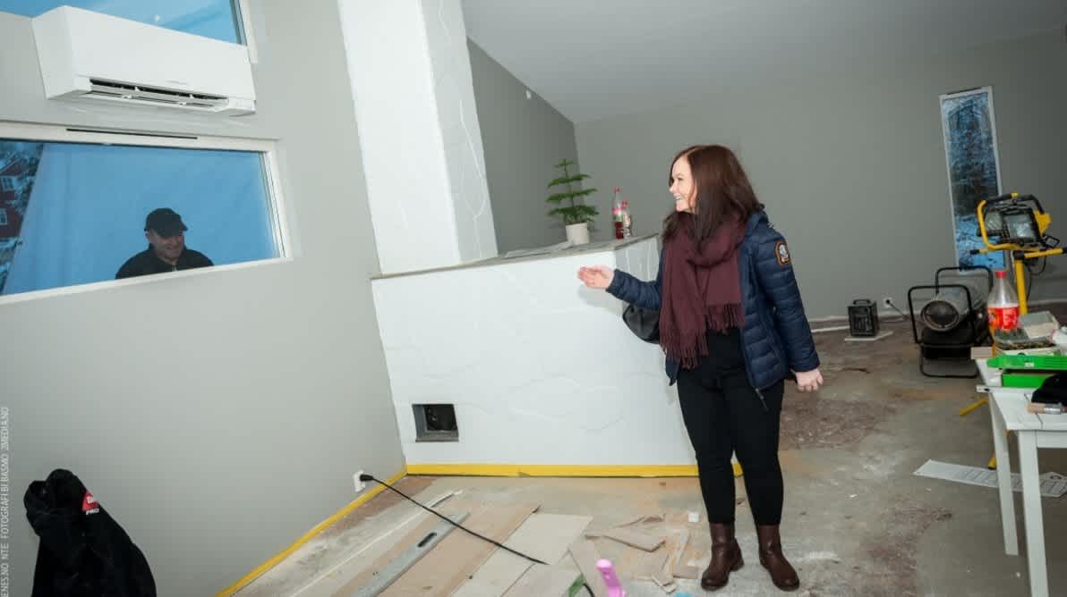 Dame i hus med varmepumpe montert pÄ veggen