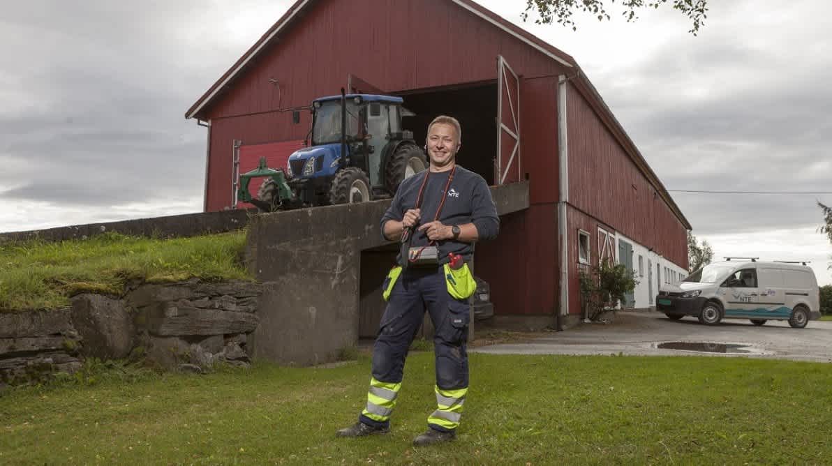 Elektriker fra NTE står foran en låve