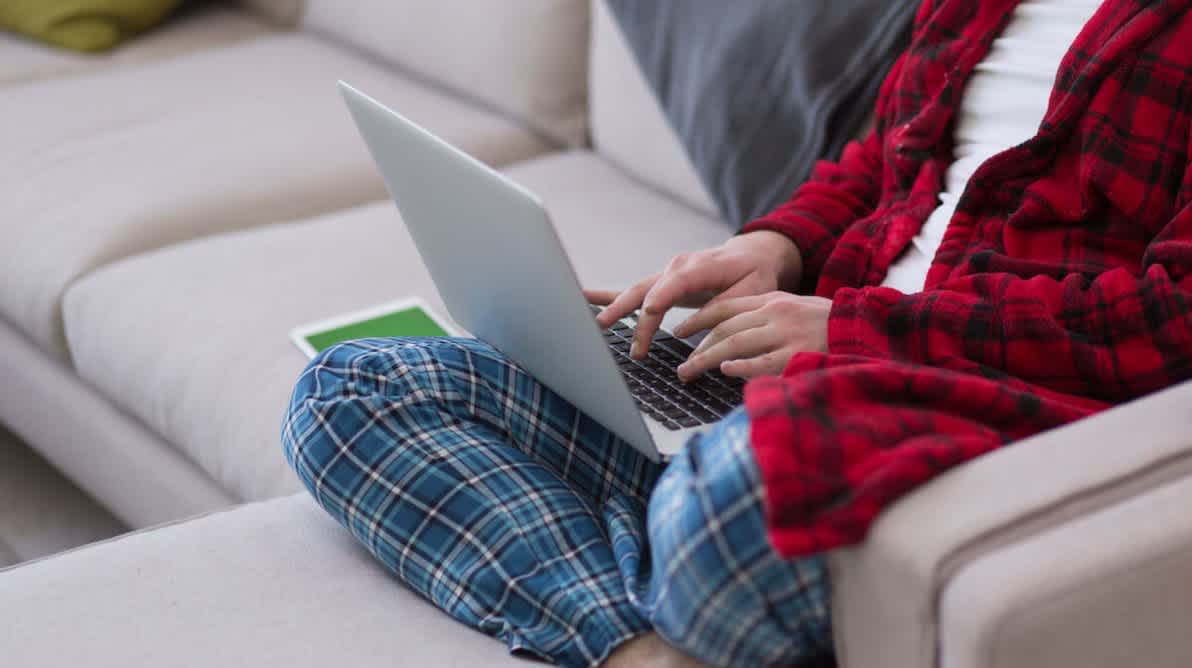 Person sitter pÄ en sofa med pc i fanget