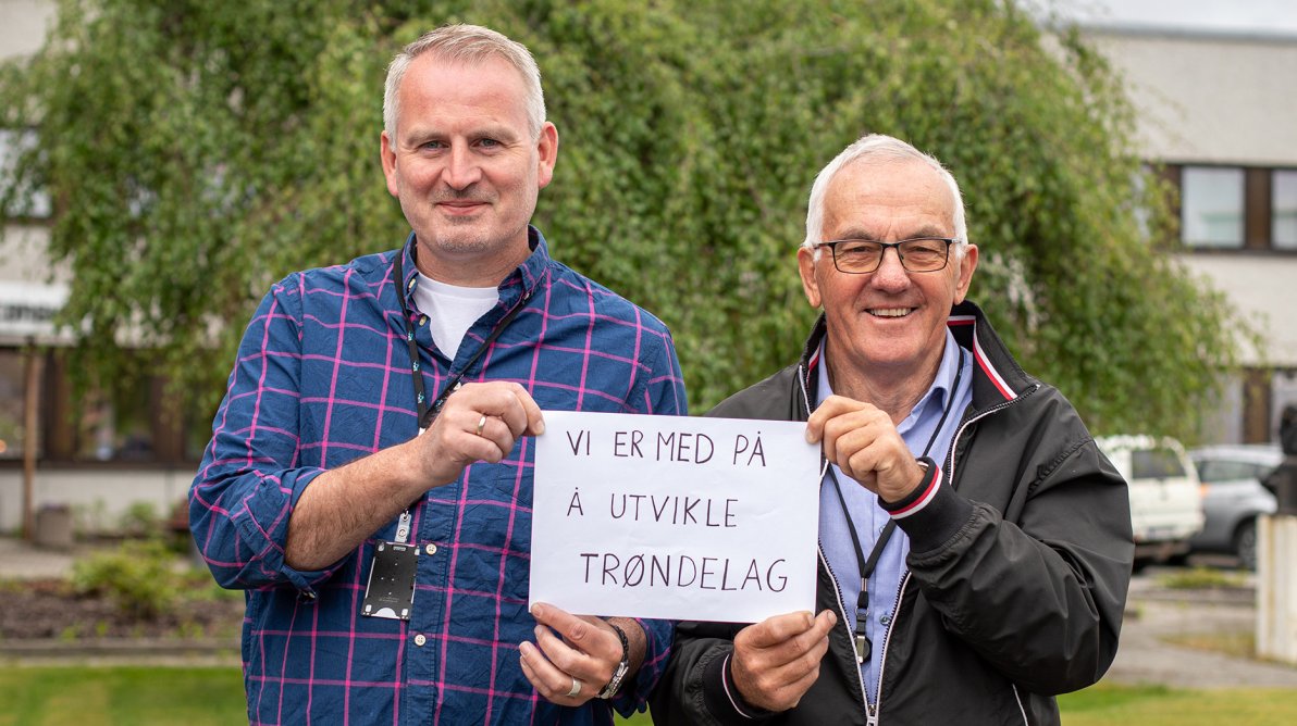 Guttorm og Tom Andre holder opp plakat som sier "Vi er med på å utvikle Trøndelag"