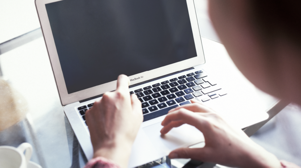 Person foran Mac med ryggen til kamera