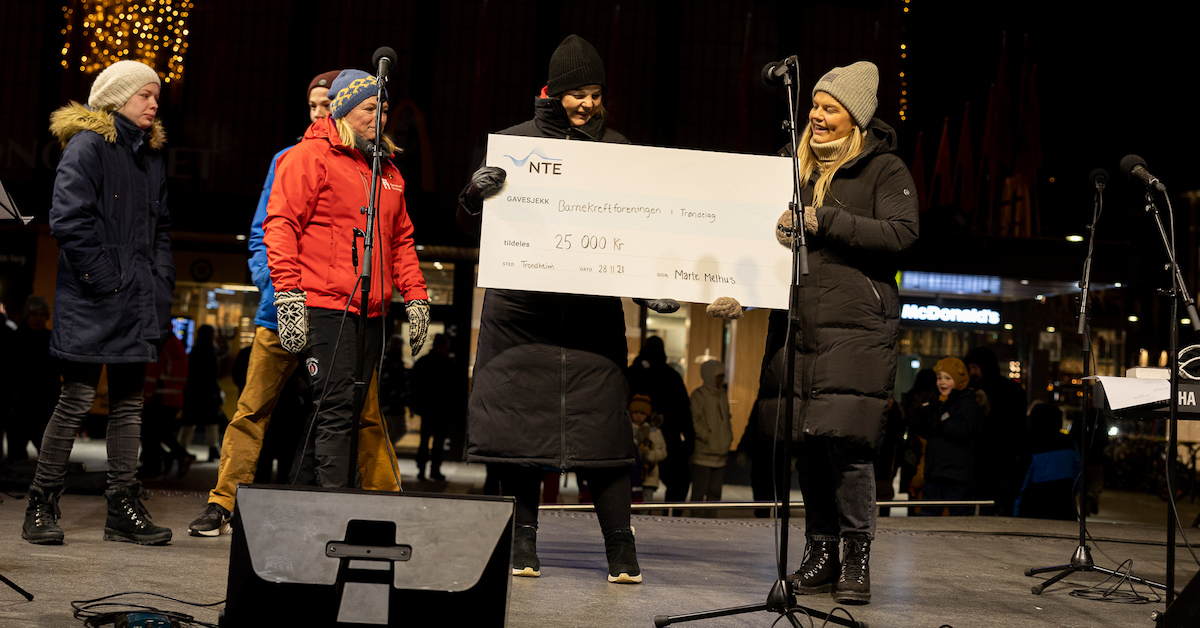 Kvinne overrekker en sjekk på 25 000 kr til en annen