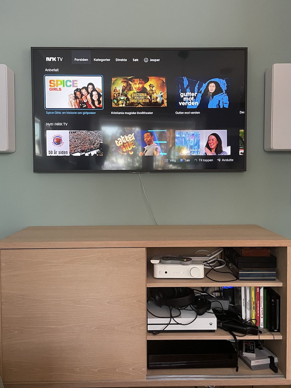 tv-benk med mange ulike spillkonsoller i og tv-en over