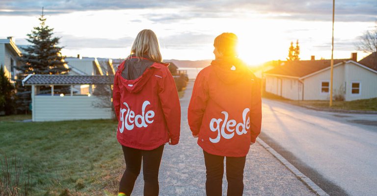 To damer som går nedover en gate i solnedgang