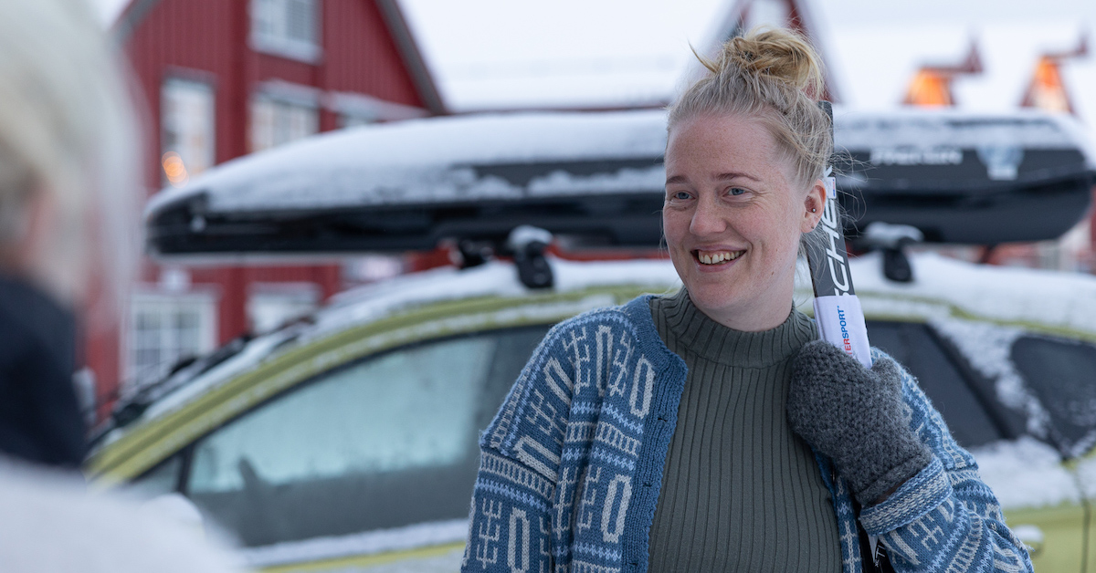 Smilende dame som holder et par ski