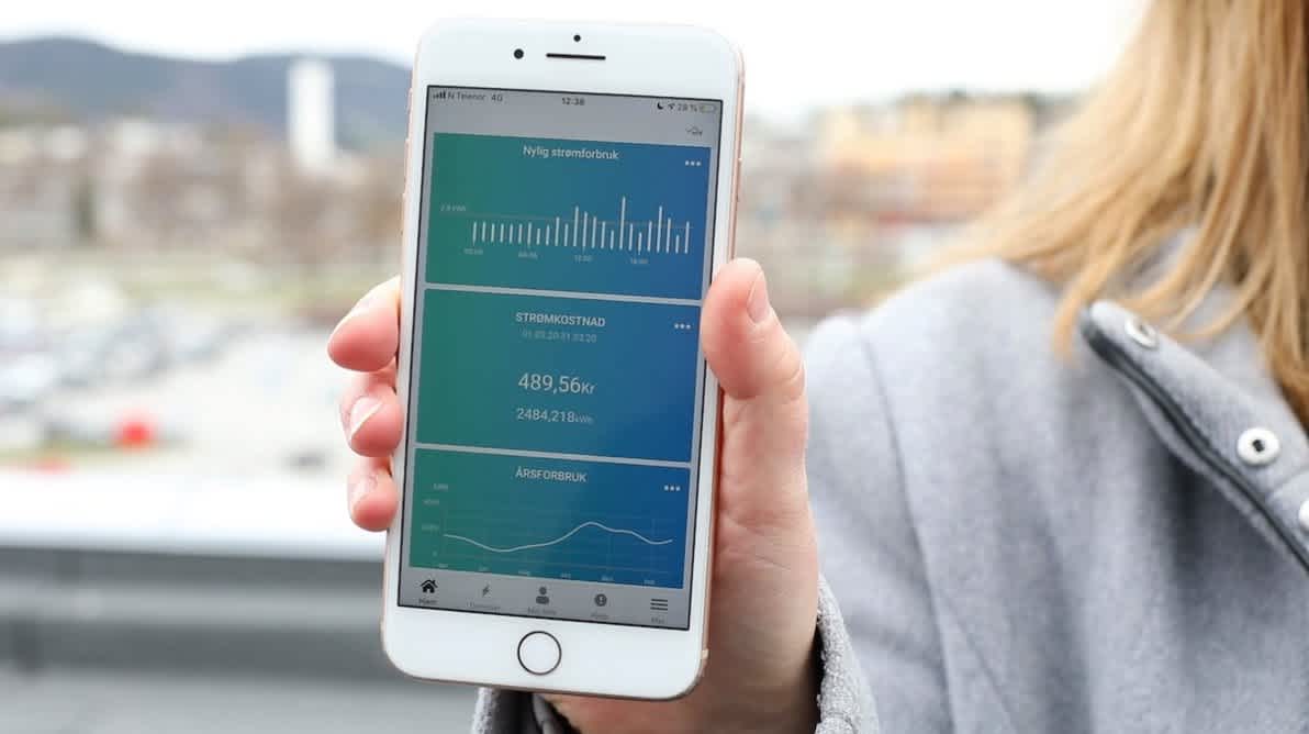 Dame som holder en iPhone med NTE appen