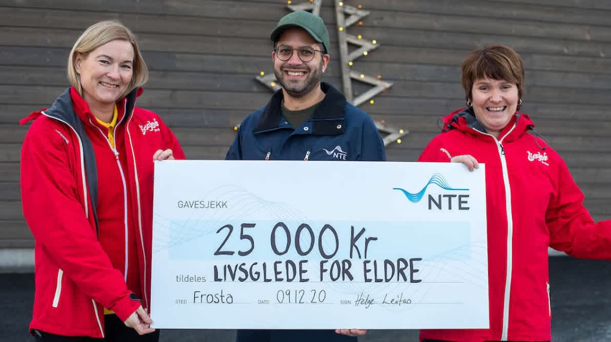 Tre smilende mennesker med en stor sjekk på 25 000kr