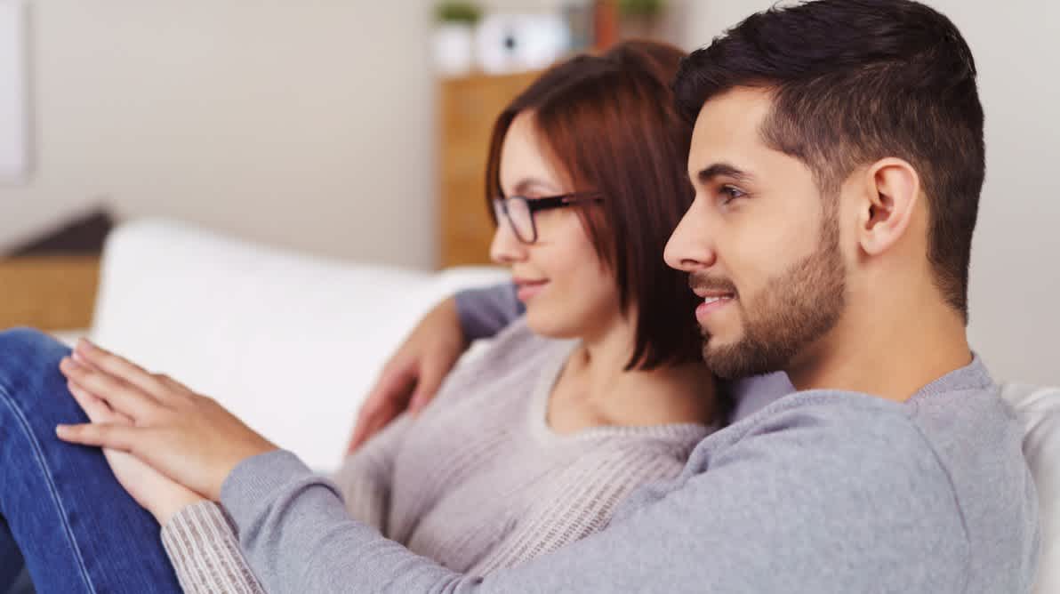 Par sitter sammen i sofa og ser pÄ TV