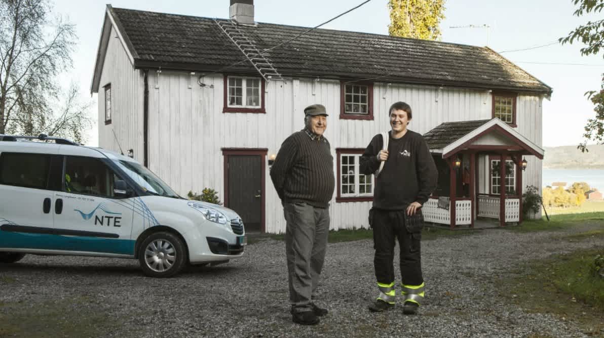Elektriker fra NTE stÄr sammen med en kunde og smiler til kamera