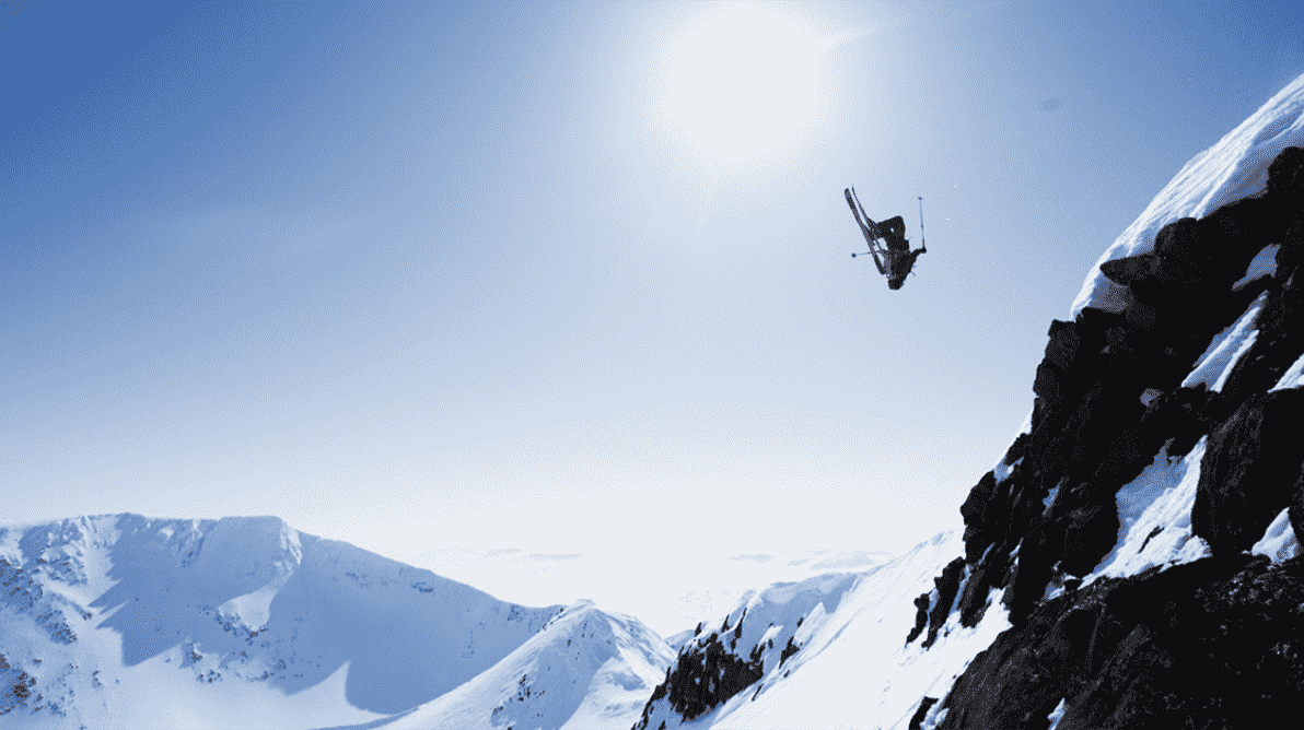 Skikjører tar salto i fritt svev ned fra et fjell