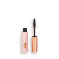 Pillow Talk Mini Mascara open Travel-size mascara in a pink-coloured tube with its gold-coloured applicator next to it.