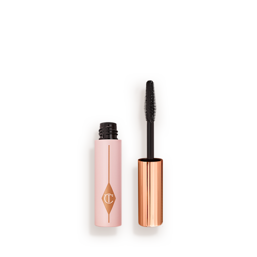 Pillow Talk Mini Mascara open Travel-size mascara in a pink-coloured tube with its gold-coloured applicator next to it.