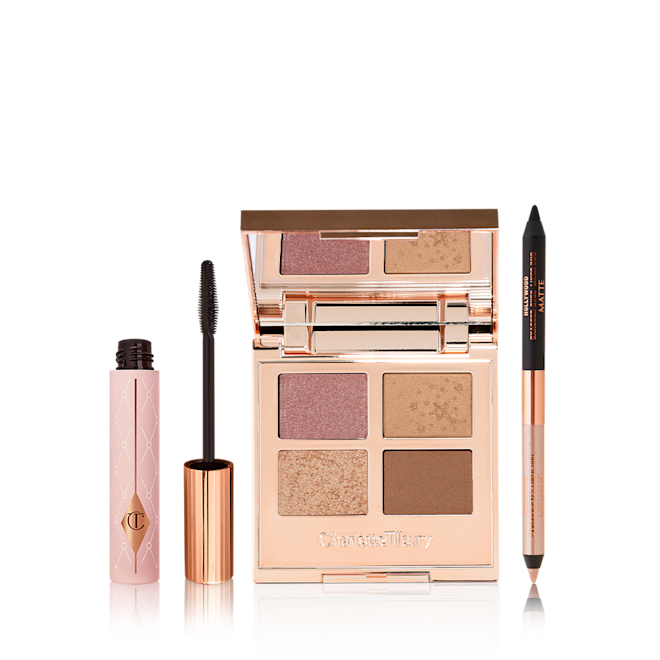 Bigger Brighter Eye Secrets open Black mascara in a sheer pink tube with a gold coloured lid and fluffy applicator, open, mirrored-lid quad eyeshadow palette with soft earthy-tones in shades of pink, brown, and gold, and a double-ended eyeliner pen in black and nude beige.